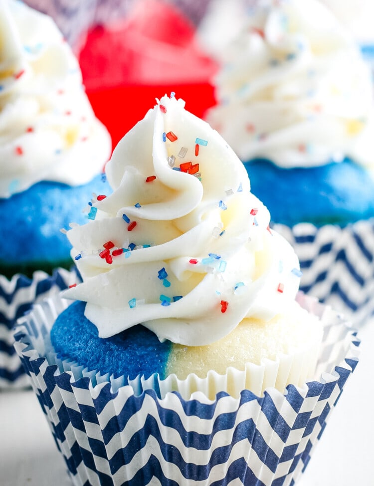 Red white and blue cupcake with white frosting and sprinkles in a chevron blue and white cupcake liner