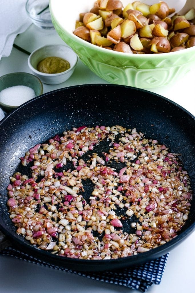 Frying pan with diced bacon being cooked