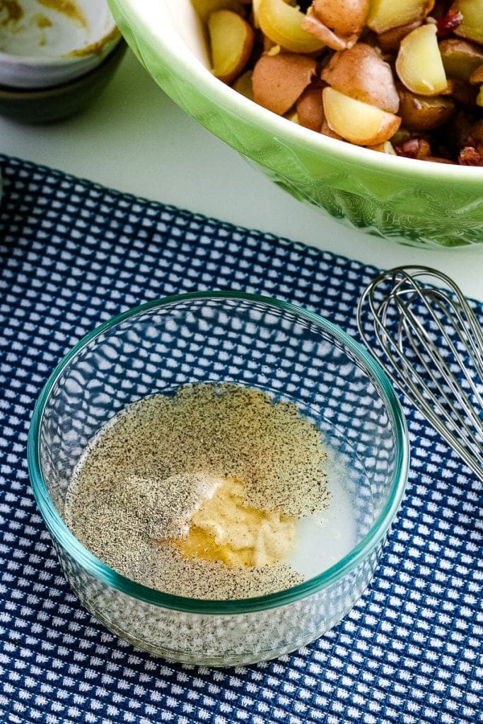 Small glass bowl with ingredients for dressing on blue napkin