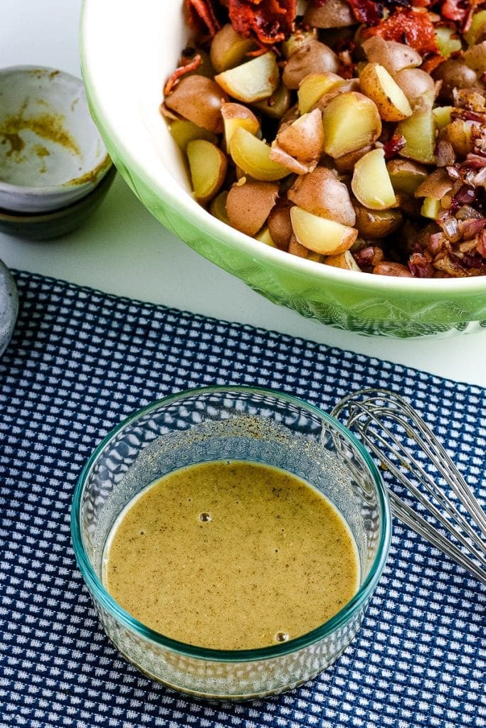 Small glass bowl with mixed salad dressing int it on blue napkin