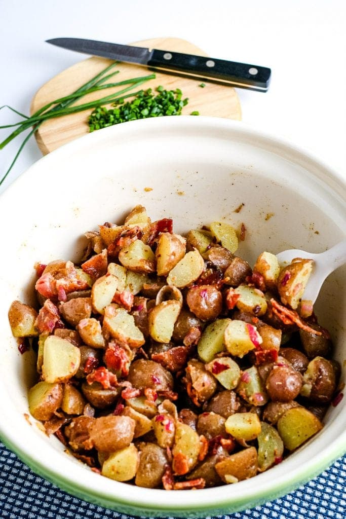 White ceramic mixing bowl with German Potato Salad in it and spoon.