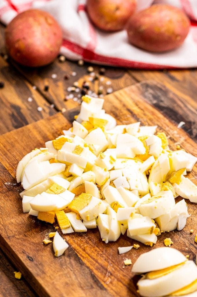Chopped hard boiled eggs on wood cutting board.