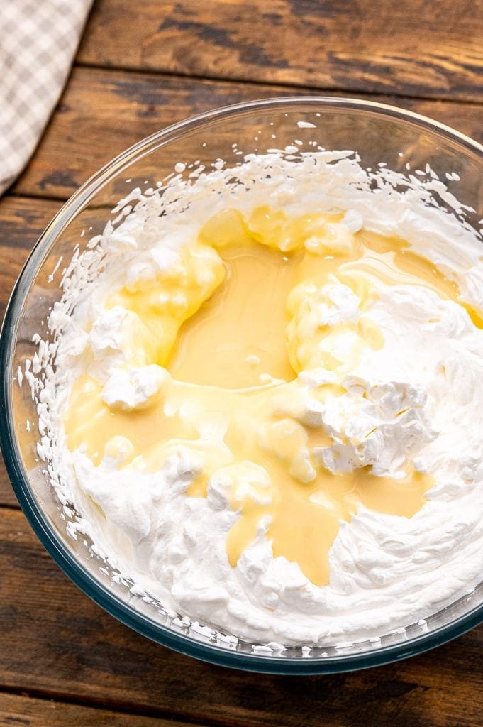 Glass bowl with homemade whipped cream and sweetened condensed milk before combining