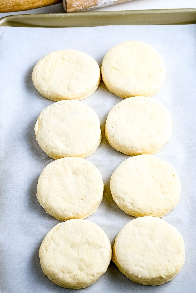 Two rows of homemade biscuits on parchment paper on a baking sheet.