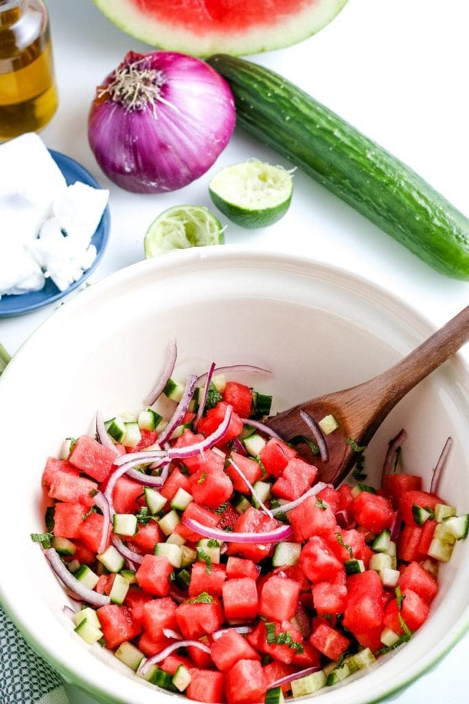 White bowl with mixed watermelon salad and wooden spoon in bowl