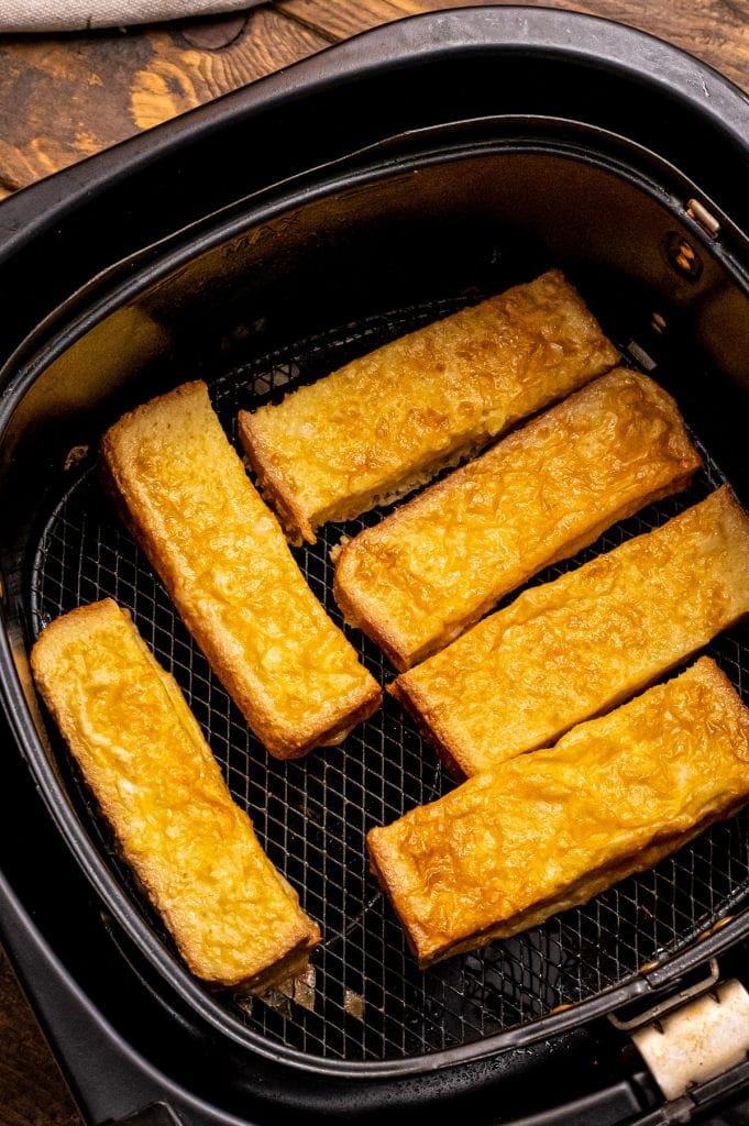 Air Fryer Basket with cooked french toast sticks in it.