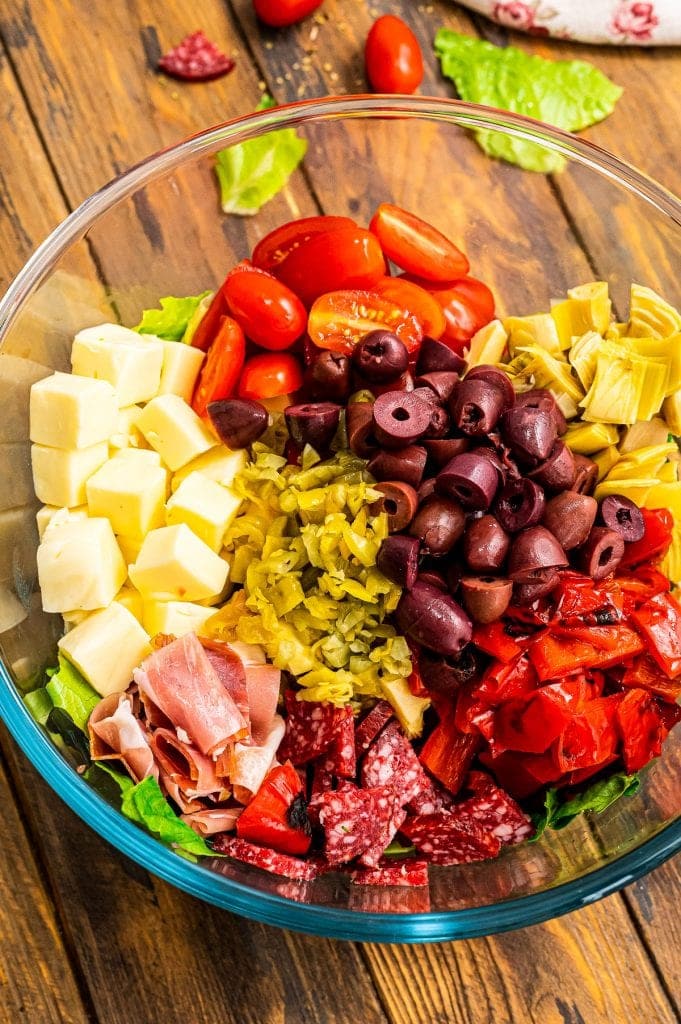 Salad ingredients in glass bowl for Antipasto salad before mixing.