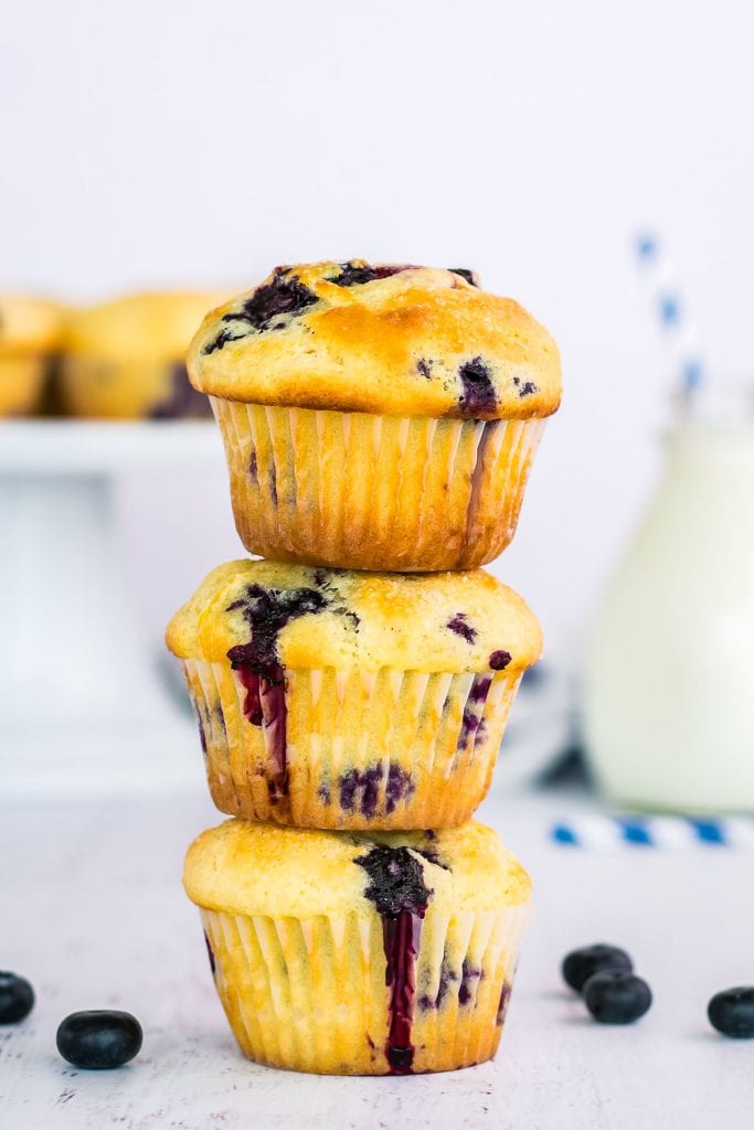 Stack of three blueberry muffins with blueberries beside them