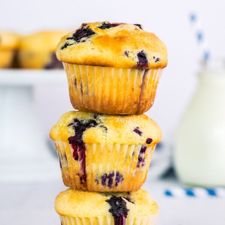 Stack of three blueberry muffins with blueberries beside them