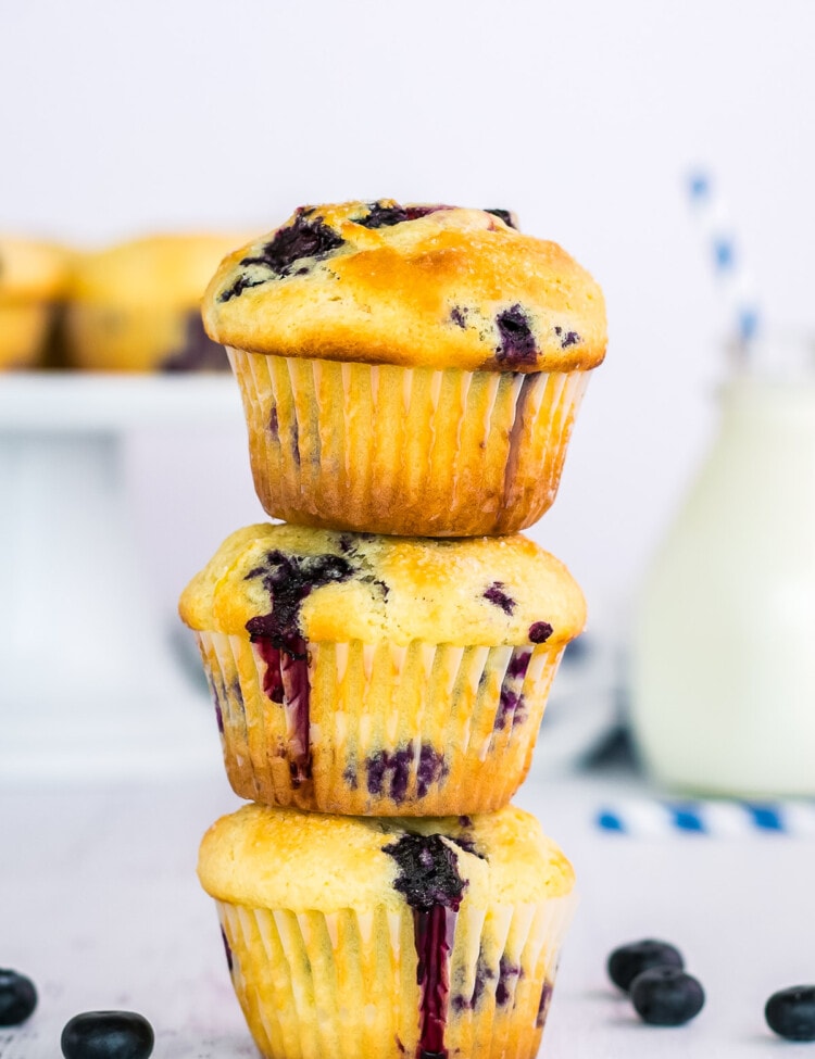 Stack of three blueberry muffins with blueberries beside them