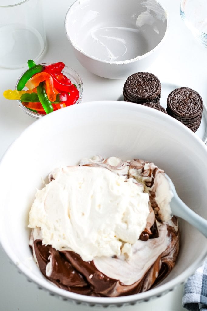 White bowl with Cool Whip and chocolate pudding before mixing together.