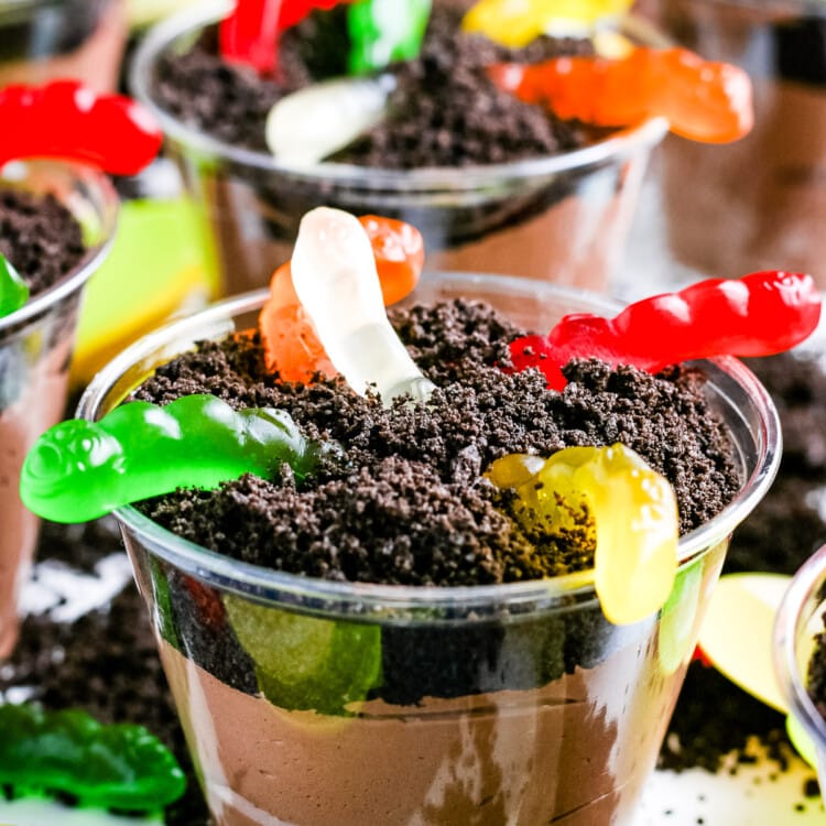 Close up of a Oreo Dirt Cup with gummy worms with more in the background.