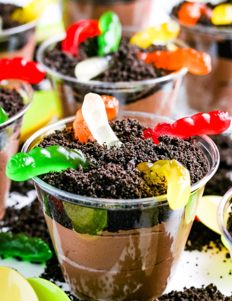 Close up of a Oreo Dirt Cup with gummy worms with more in the background.