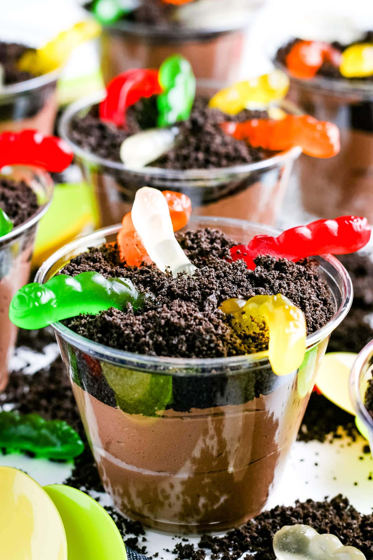 Close up of a Oreo Dirt Cup with gummy worms with more in the background.