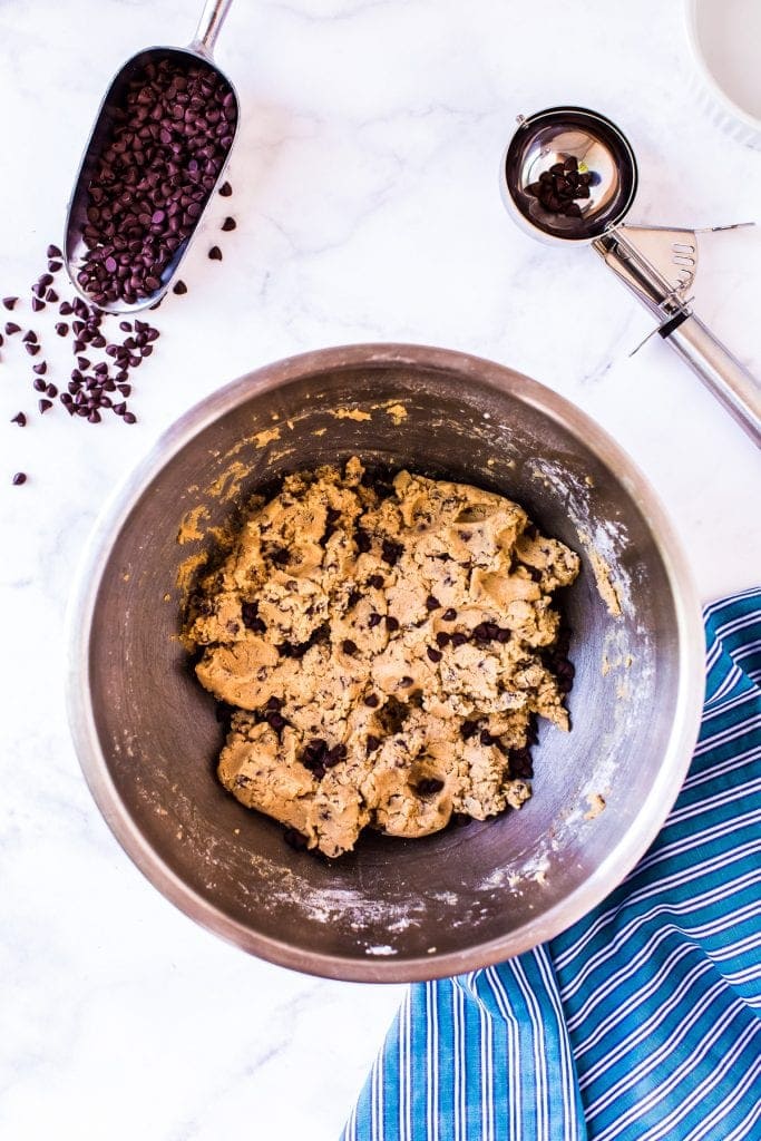 Mixed Edible Cookie Dough in overhead image in a stainless steel bowl with a blue napkin and chocolate chips next to it.