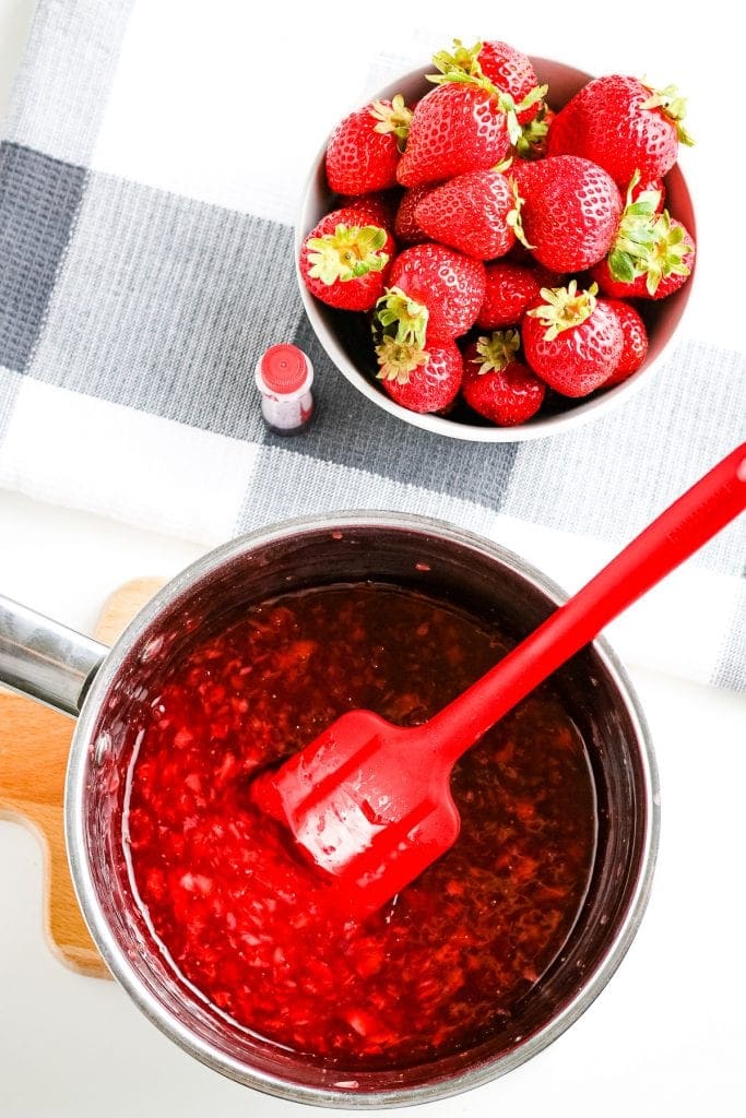 Cooked strawberry sauce with red spatula in it.