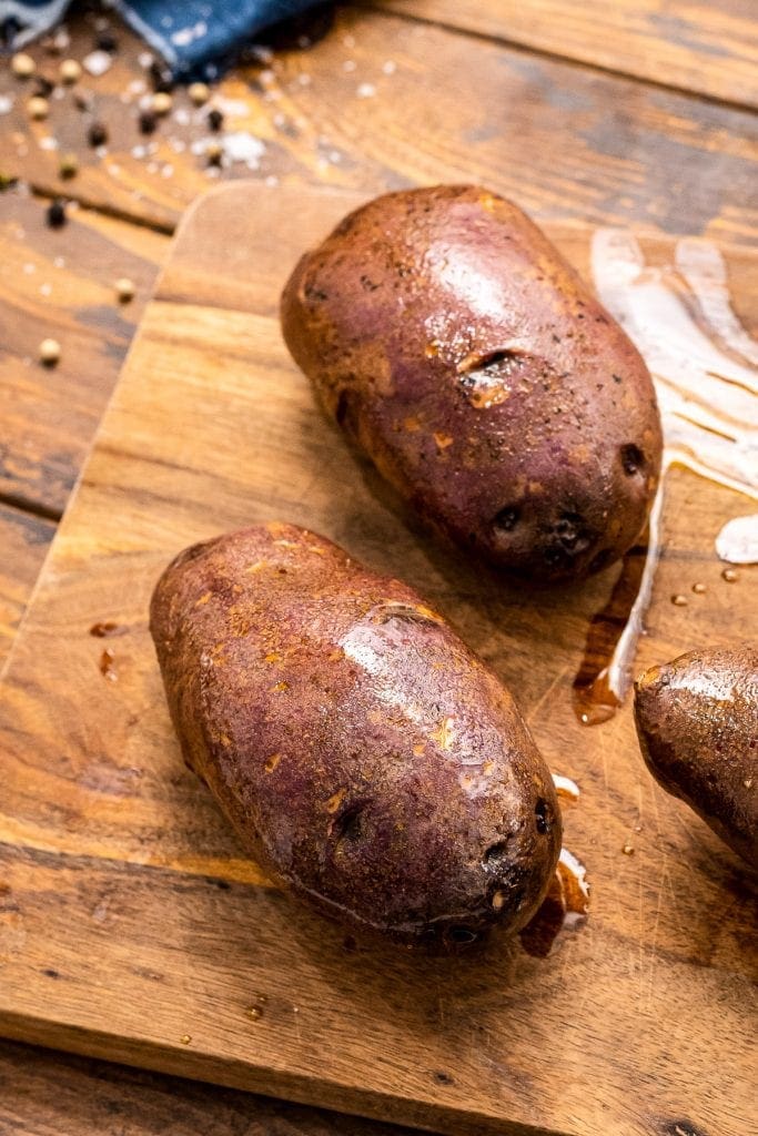 Potatoes coated in oil on a wooden in cutting board