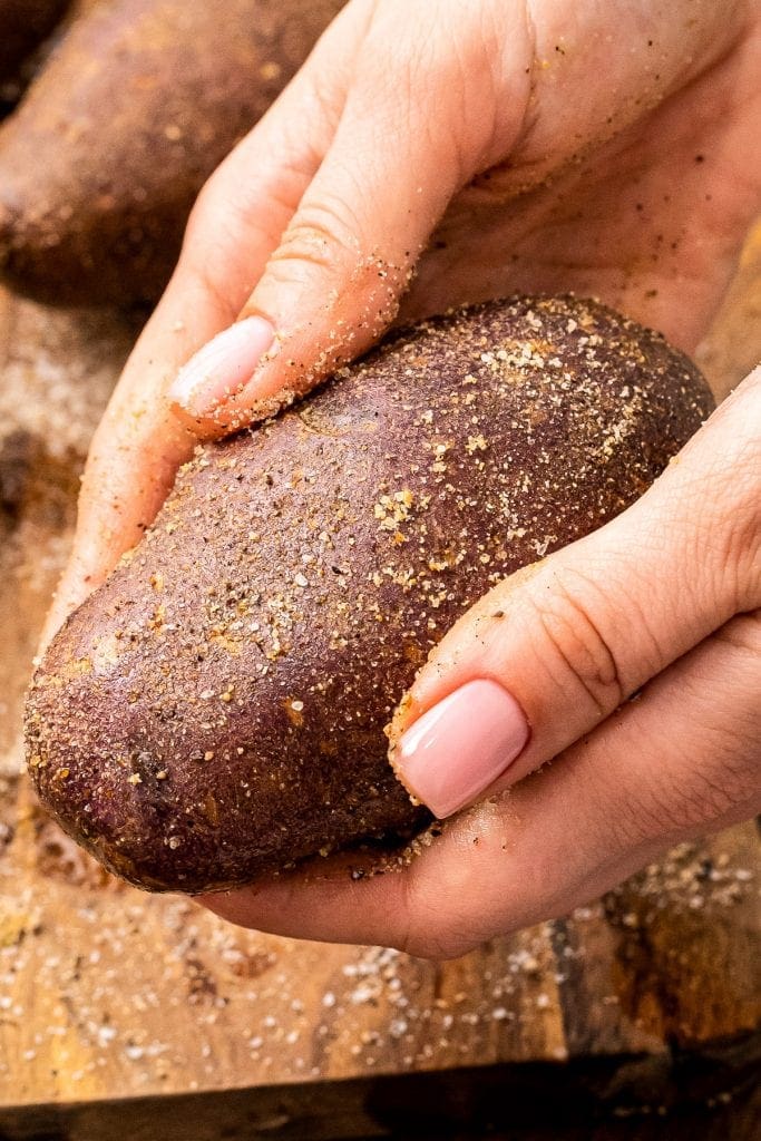 Hand holding a potato with seasoning on it
