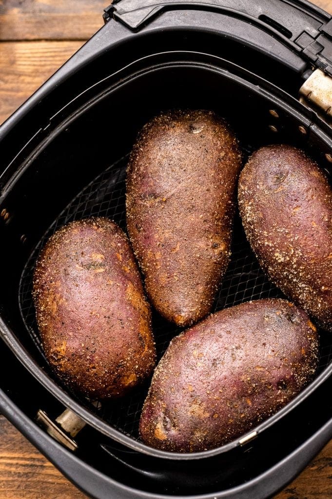 Air Fryer basket with seasoned potatoes in it