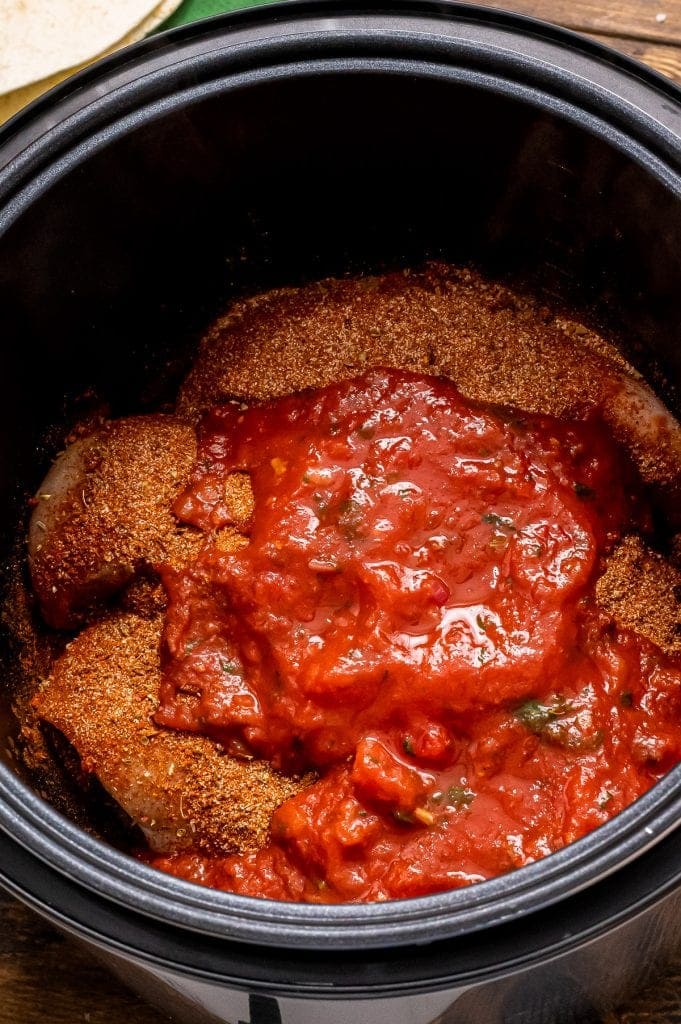 Black Instant Pot liner with uncooked chicken breasts, taco seasoning and salsa
