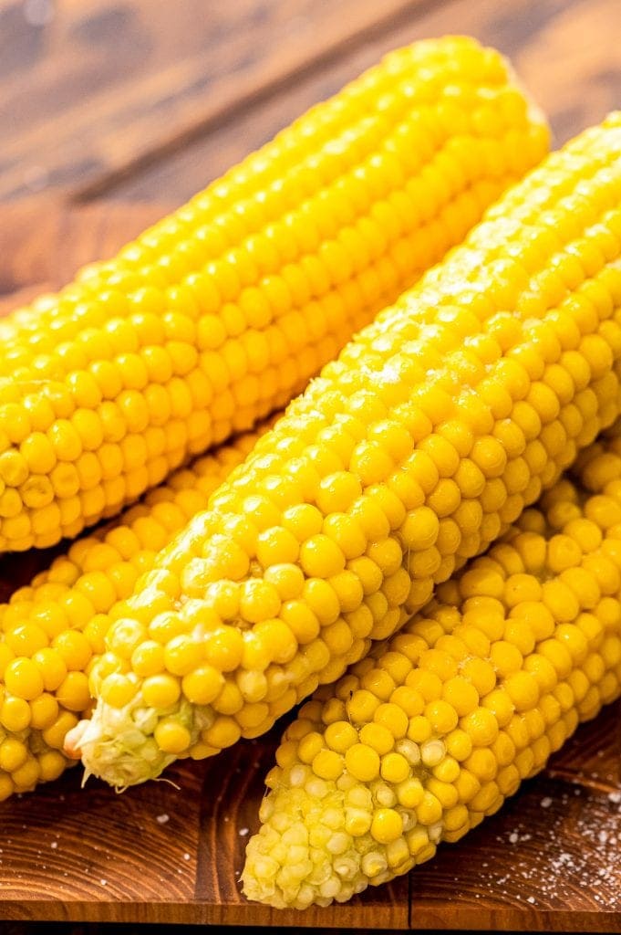 Portrait image showing cooked corn on the cob that is slightly stacked.