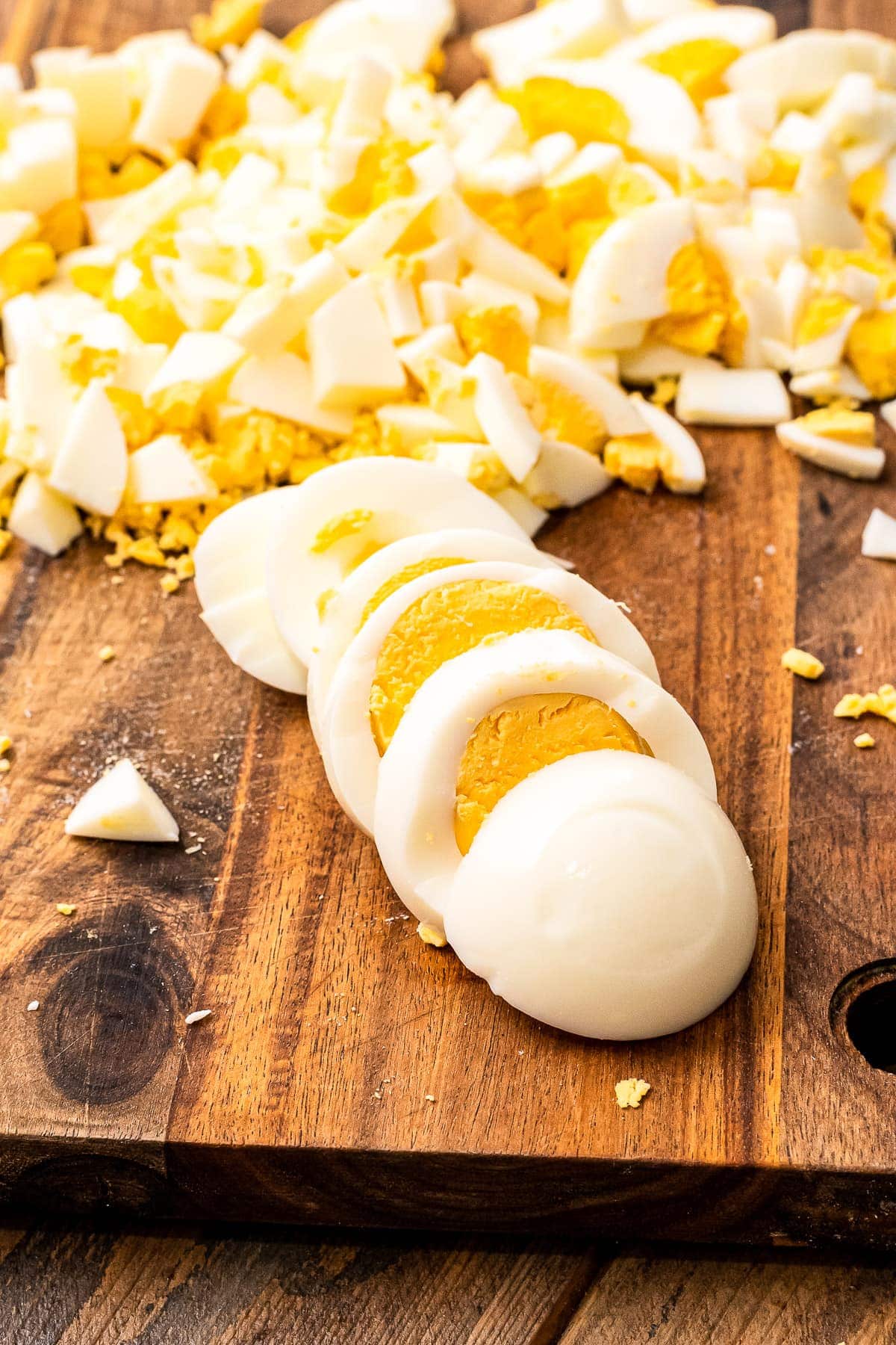 Wood cutting board with hard boiled eggs sliced on it.