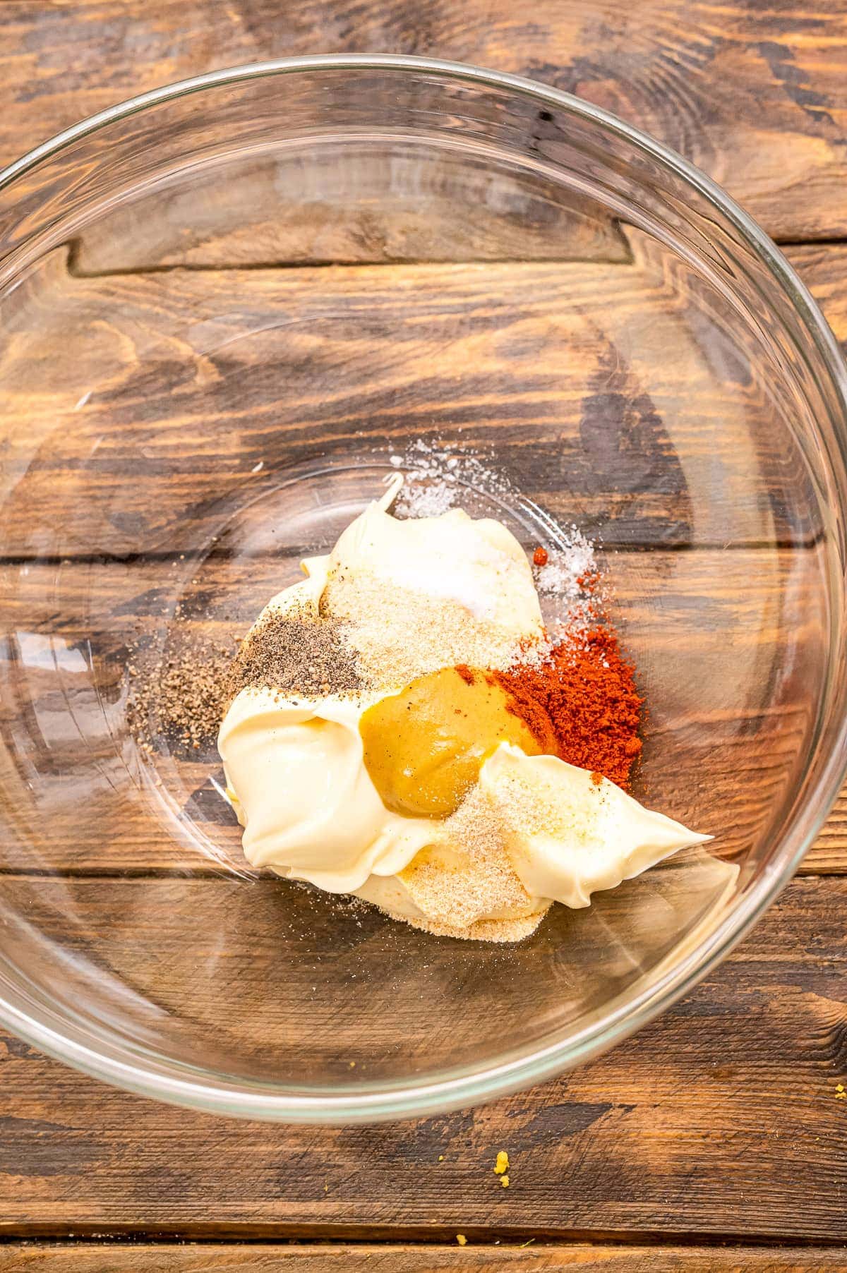 Glass bowl with dressing ingredients for potato salad before mixing.