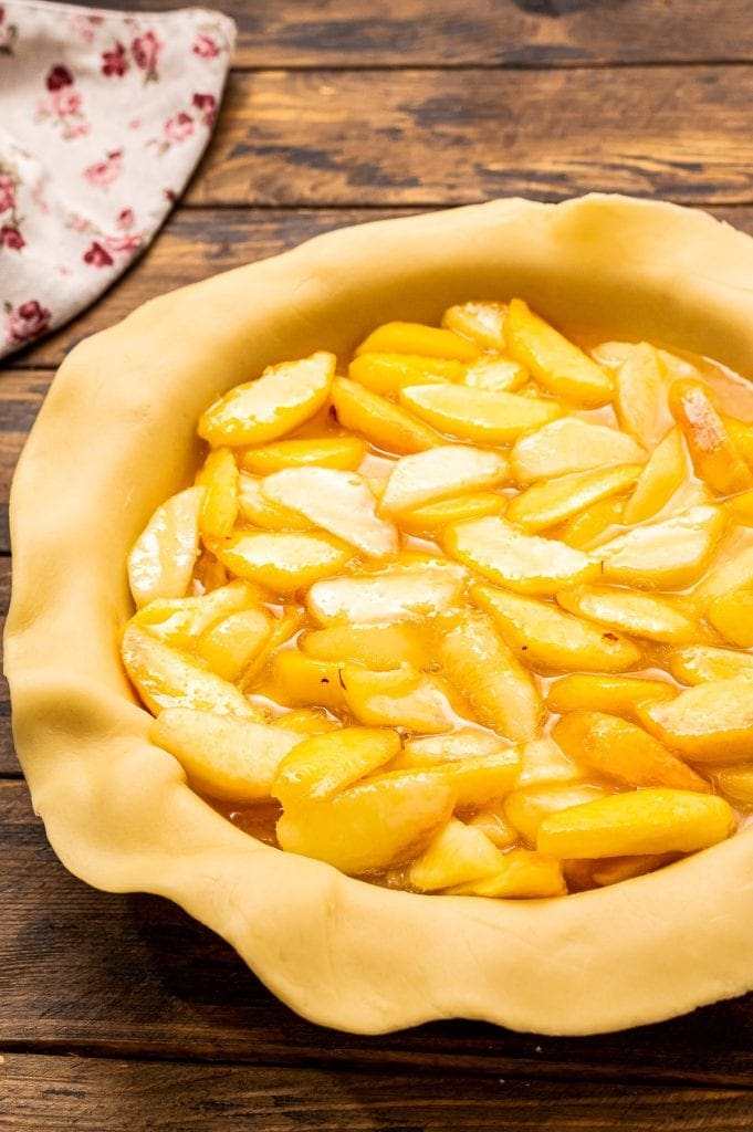 Pie Crust in pie dish filled with peach pie filling.