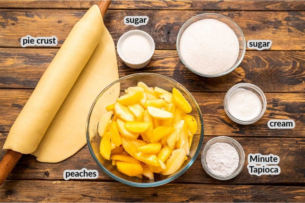 Overhead image of ingredients for peach pie including crust, peaches, sugar, cream, tapioca.