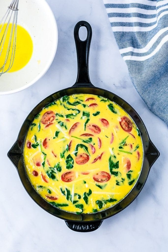 Cast Iron skillet with ingredients for Spinach Frittata in it
