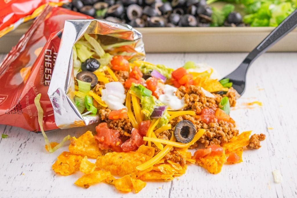 Small Dorito bag spilling walking taco onto white background.