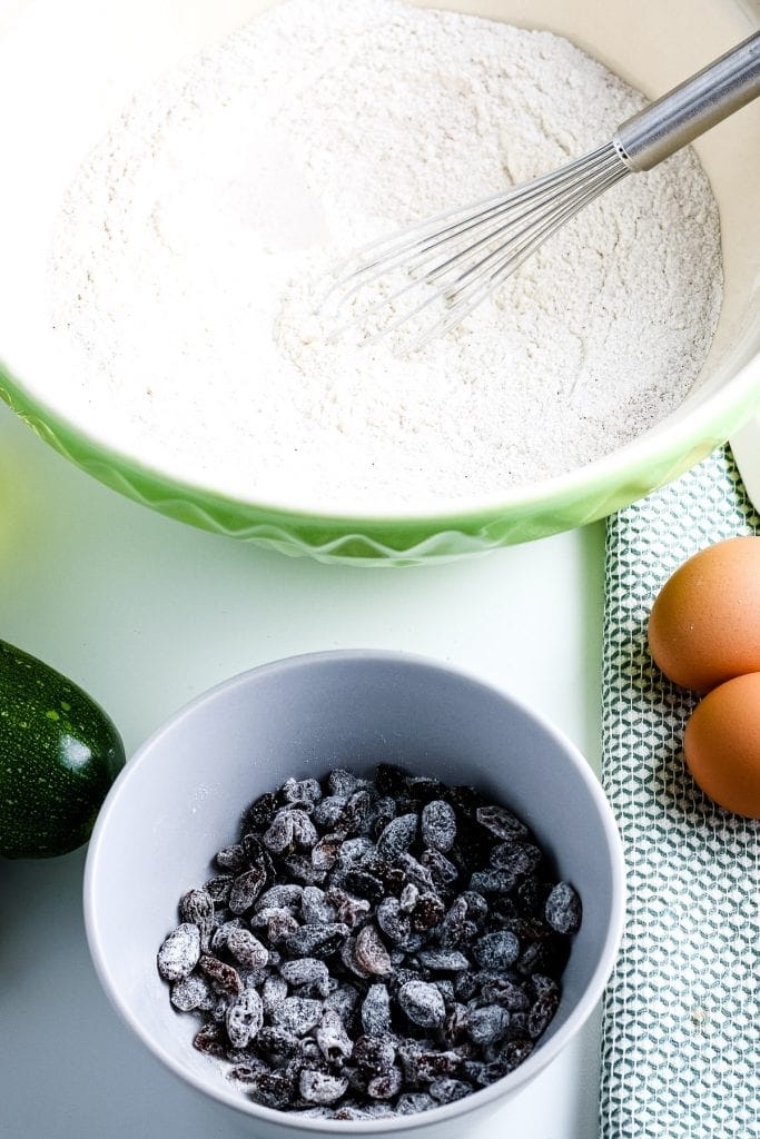 Raisins in bowl tossed with flour.