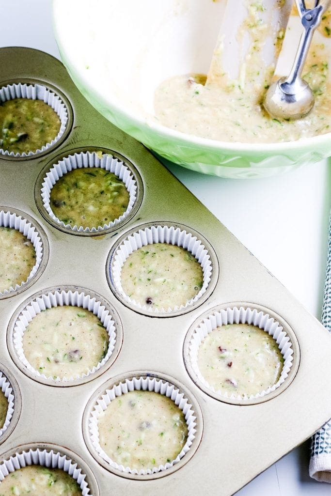 Zucchini Muffin batter in muffin pan lined with muffin liners.