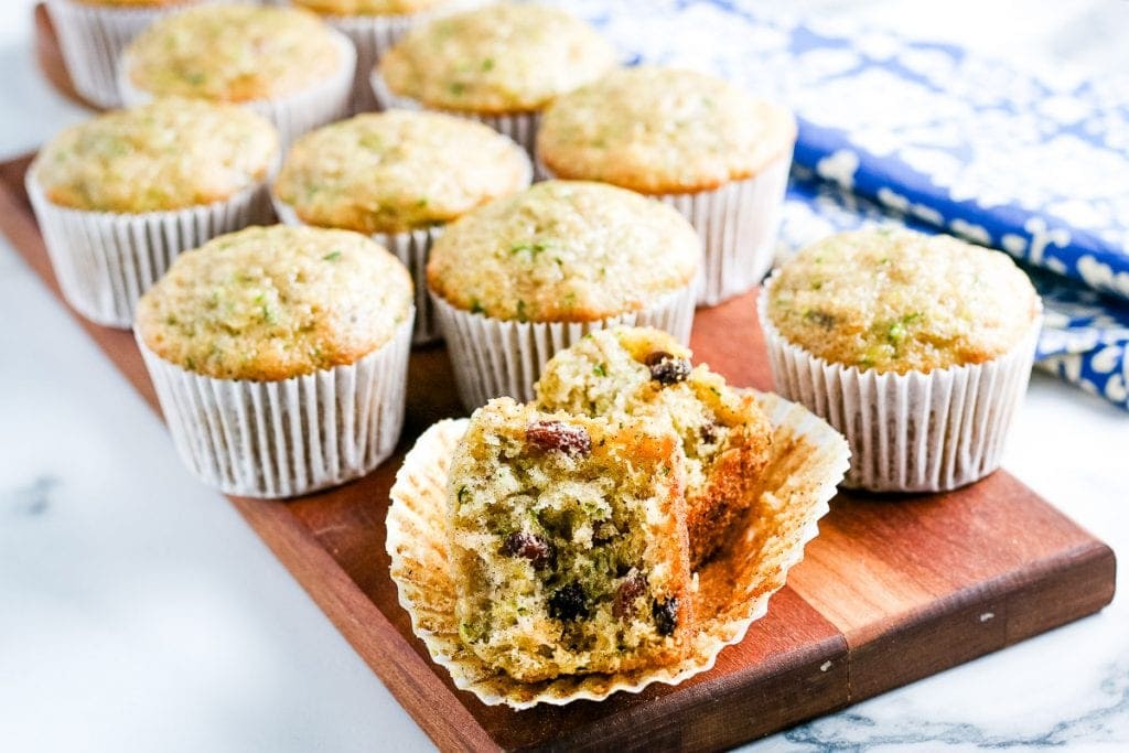 Zucchini muffin cut in half on muffin liner with more muffins behind it.