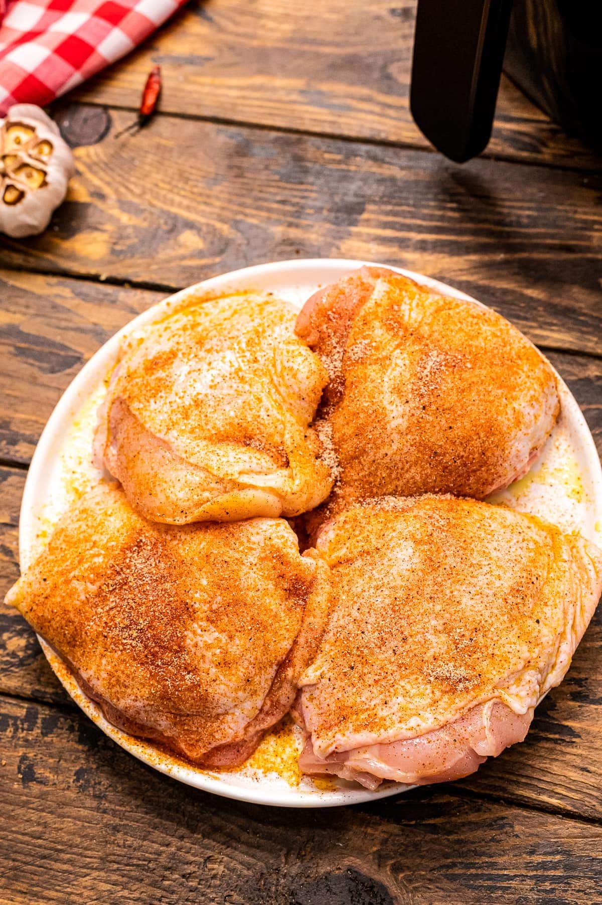 Plate on it with seasoned 4 raw chicken thighs on it