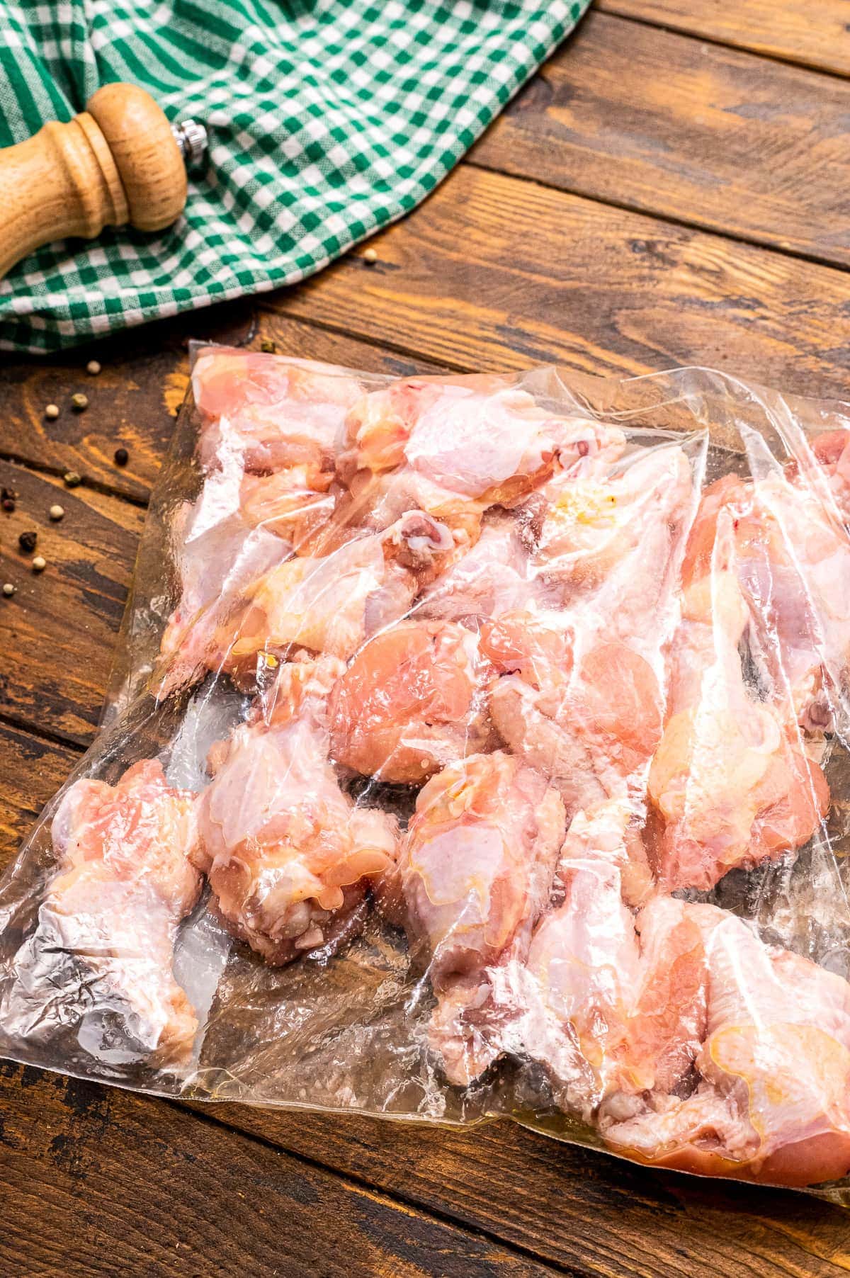 Ziplock bag with chicken wings in it and oil on wood background.