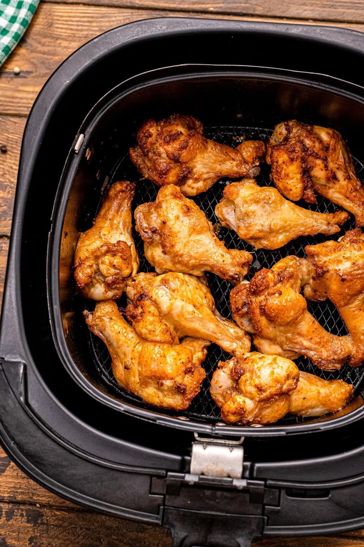 Air Fryer basket with cooked chicken wings in it.