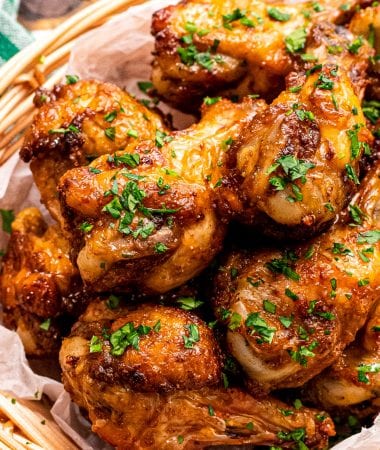 A bowl with crispy chicken wings in it garnished with chopped parsley.