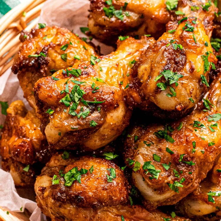 A bowl with crispy chicken wings in it garnished with chopped parsley.