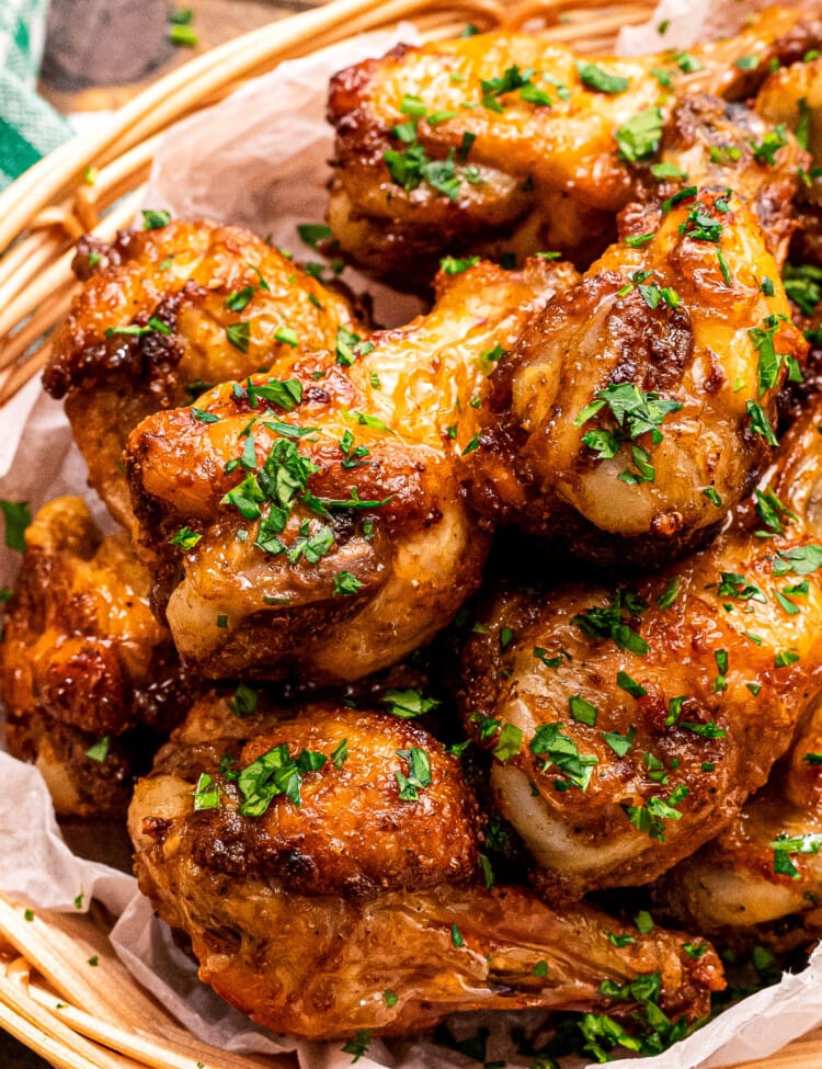 A bowl with crispy chicken wings in it garnished with chopped parsley.