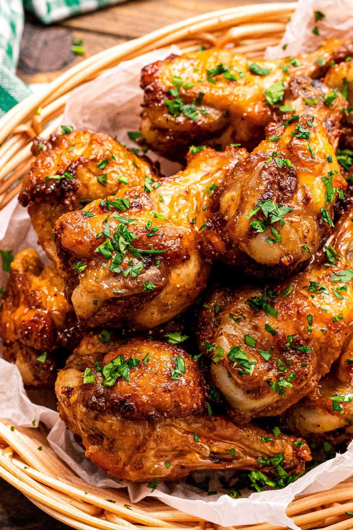 A bowl with crispy chicken wings in it garnished with chopped parsley.