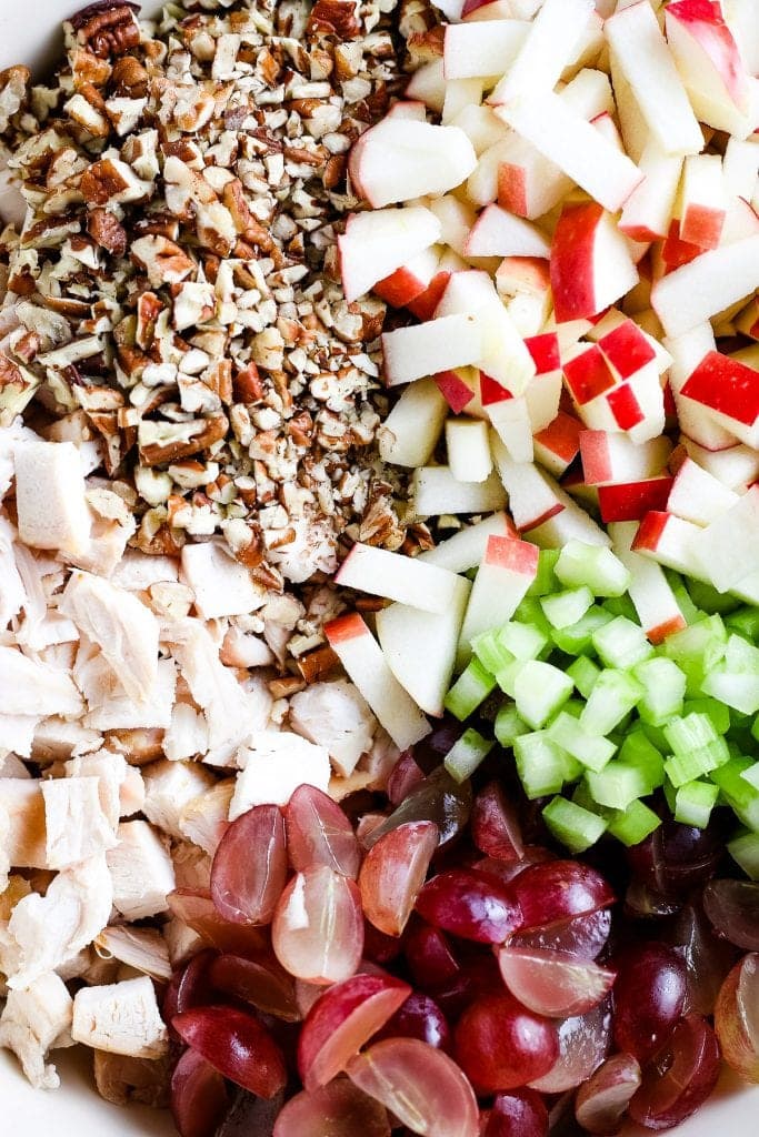 Close up image showing chopped, chicken, grapes, celery, apples and nuts before mixing.