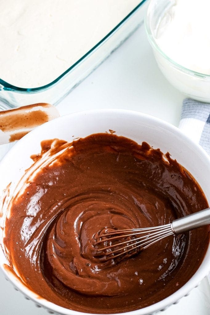 White bowl with chocolate pudding mixed in it. Whisk sitting in the bowl.