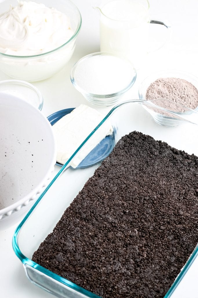 Glass baking dish with an oreo crust pressed into it.