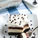 Square white dish with a piece of No Bake Chocolate Lasagna. A fork with a bite on it laying next to it.