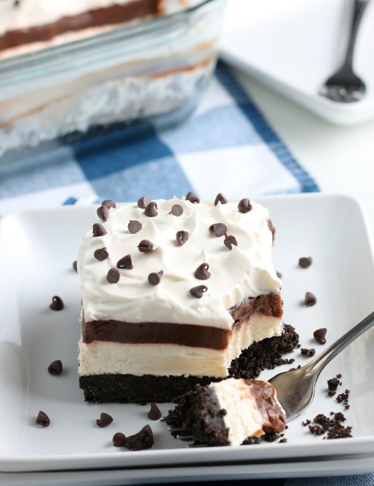 Square white dish with a piece of No Bake Chocolate Lasagna. A fork with a bite on it laying next to it.