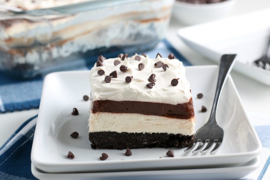 Square white dish with a piece of chocolate lasagna and a fork laying next to it.
