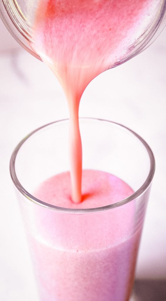 Smoothie being poured out of blender into a glass