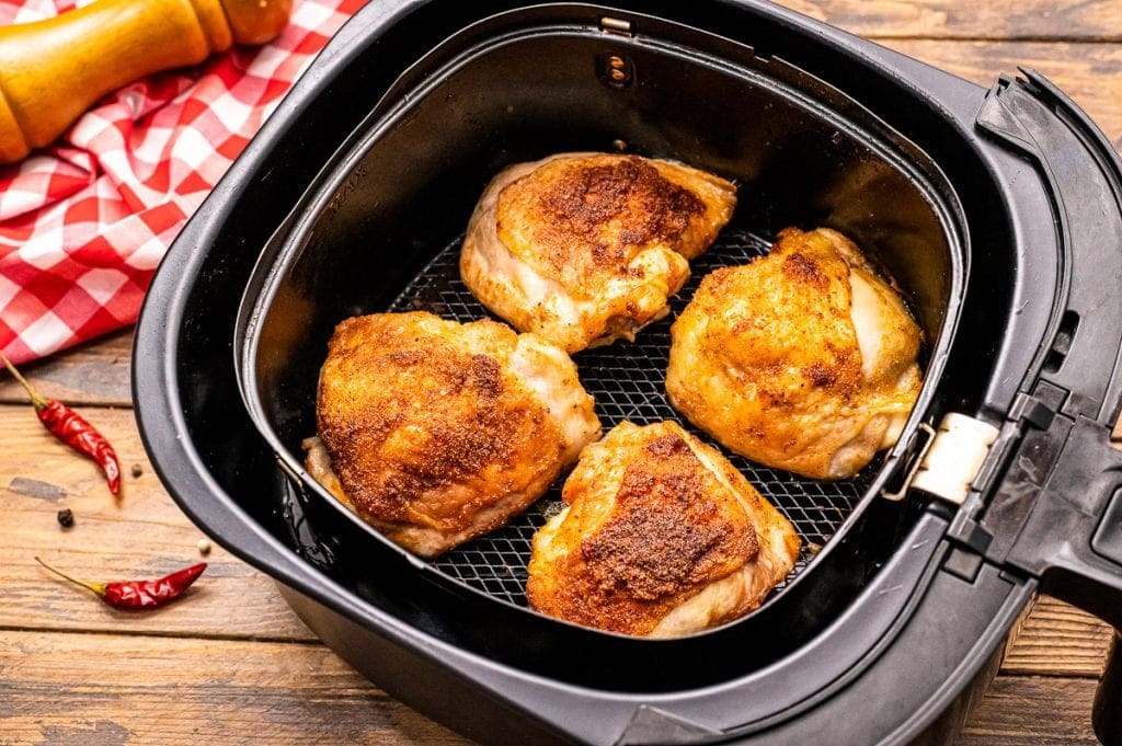Air Fryer basket with cooked chicken thighs in it