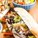 Wood cutting board with two hoagies filled with Italian Beef